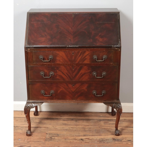 592 - A mahogany three drawer bureau with fitted interior raised on ball and claw feet.