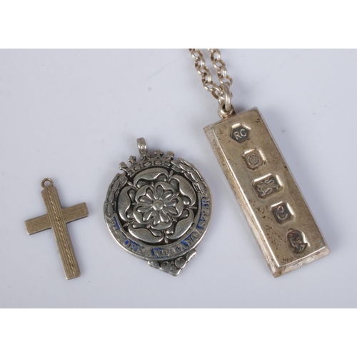 528 - A collection of silver pendants to include silver ingot on chain, cross-country running fob awarded ... 