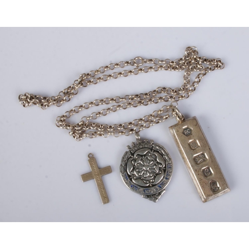 528 - A collection of silver pendants to include silver ingot on chain, cross-country running fob awarded ... 