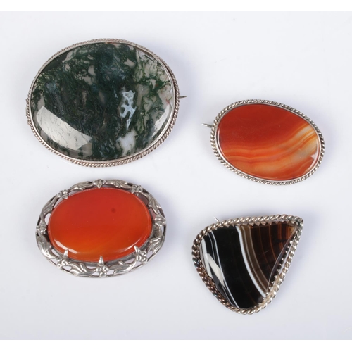 553 - Four agate set silver mounted brooches. One example stamped, all others test as silver.