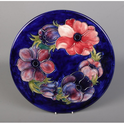 562 - A Moorcroft pottery charger with dark blue ground base decorated in the Anemone pattern. Approx. dia... 