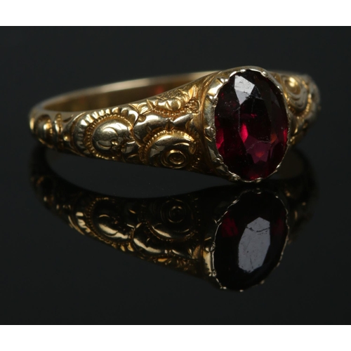 517 - A 12ct Gold ring set with central garnet on scrolled shoulders. Size K½. Total weight: 2.1g.