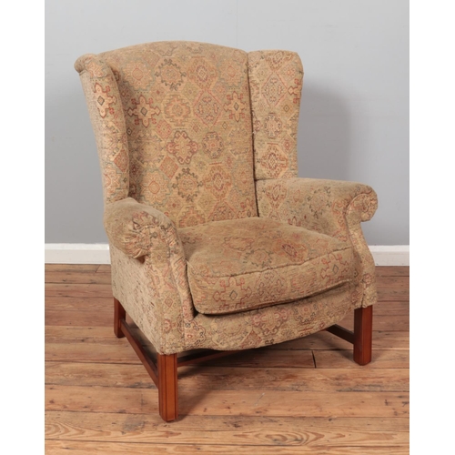 596 - A wing back arm chair raised on square cut legs.