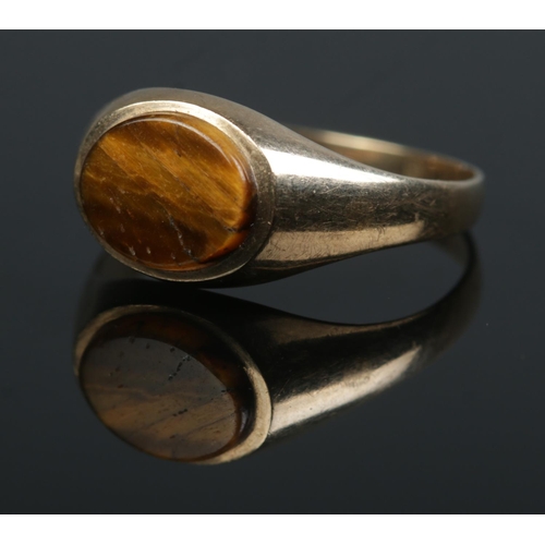 473 - A 9ct gold ring set with a Tiger's Eye stone. Size R. 2g.