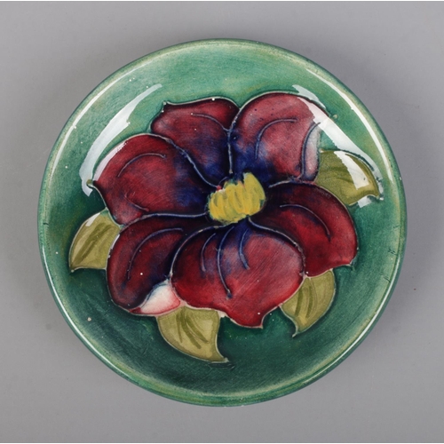 496 - A small Moorcroft pottery pin dish in the Clematis pattern. Bears original Queen Mary paper label to... 