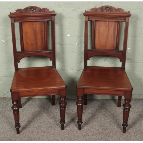 557 - A pair of mahogany carved hall chairs.