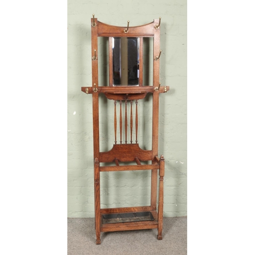 579 - An early 20th century oak hall stand of slender proportions with mirrors panel and brass coat hooks.... 