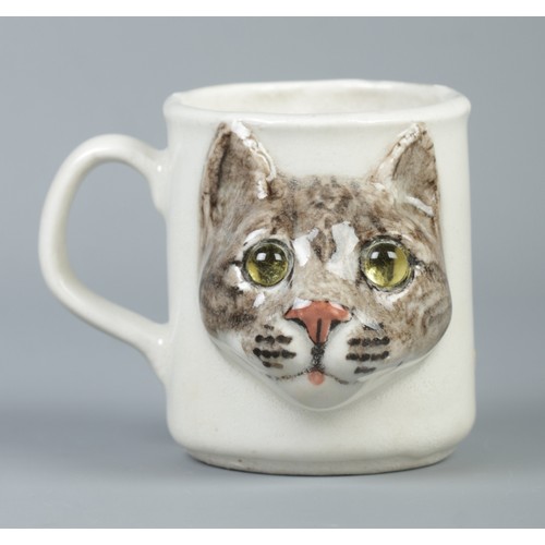 514A - An I. Winstanley decorative pottery cup featuring cat's face with glass eyes. Signed to base and num... 