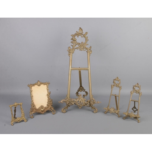 15 - Five decorative brass photograph frames and display stands, all on easel backs. Tallest: 56cm.