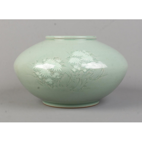 151 - An oriental celadon bowl, depicting floral scene to the front. Bears character marks to the base. To... 