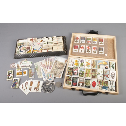 23 - A quantity of cigarette cards along with a small quantity of European banknotes. Includes John Playe... 