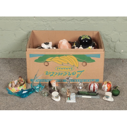 276 - One box of miscellaneous items. To include dolls, ceramic apple paperweights, glass dolphins, lidded... 