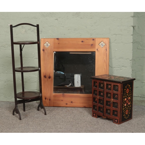 295 - A mahogany three tier folding cake stand, together with a small table top cabinet and pine mirror.