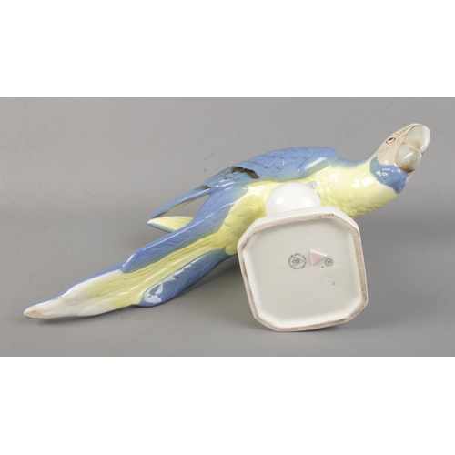 486 - A Royal Dux ceramic blue macaw parrot posed on a small perch. Approx. height 12cm.