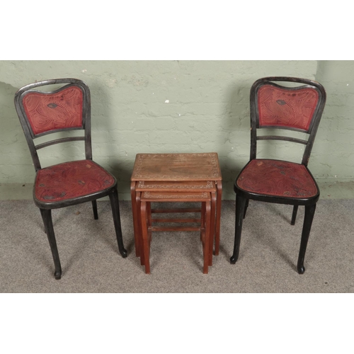 559 - A pair of painted side chairs with a small carved nest of tables.