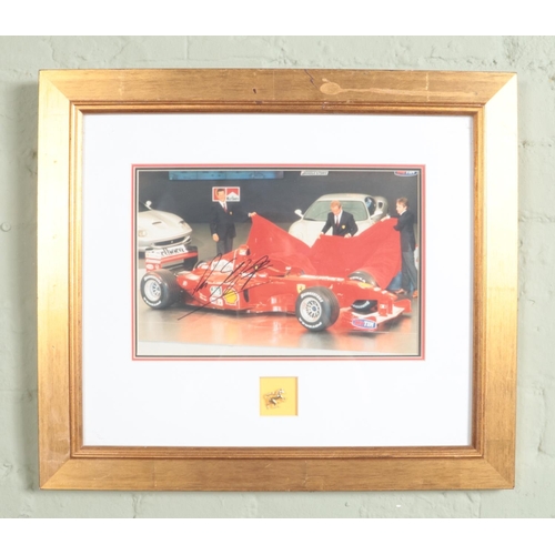 319 - A framed and signed photograph showing Michael Schumacher unveiling a Ferrari F1 car. With certifica... 