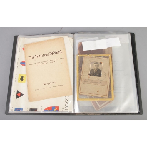 455 - A folder holding a collection of war time militaria including Hitler Youth documents, cuff titles, f... 