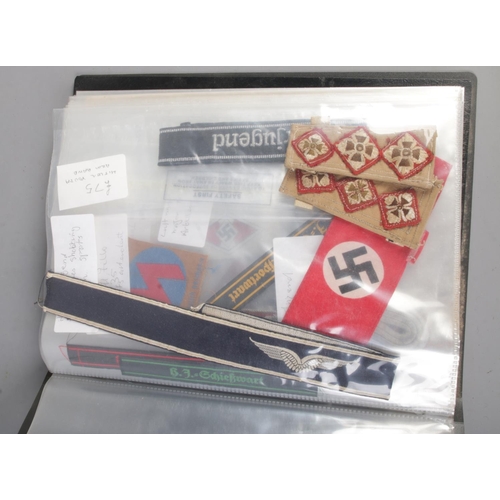 455 - A folder holding a collection of war time militaria including Hitler Youth documents, cuff titles, f... 