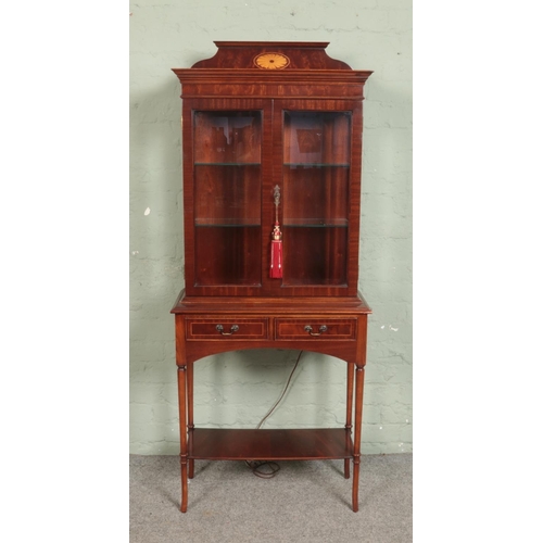 510 - A mahogany display cabinet featuring shell fan pattern, glass shelving, built-in light and two drawe... 