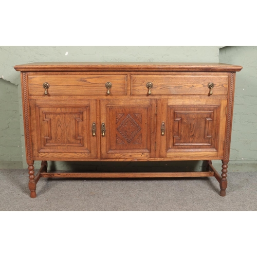 521 - An oak sideboard on bobbin turned supports, with two drawers above three cupboard doors and having c... 