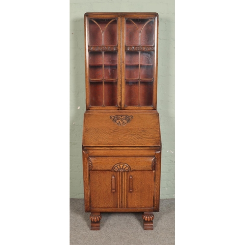 524 - A carved oak bureau bookcase, with glazed top with adjustable shelving and fall down front revealing... 