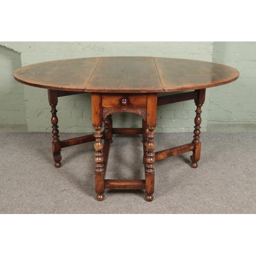 527 - An antique carved oak gateleg dining table, with bobbin turned supports and drawer to one side. Heig... 