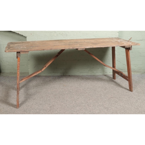 542 - A folding pine topped trestle table bearing stamp for Northern Table and Chair Hire to top. Approx. ... 