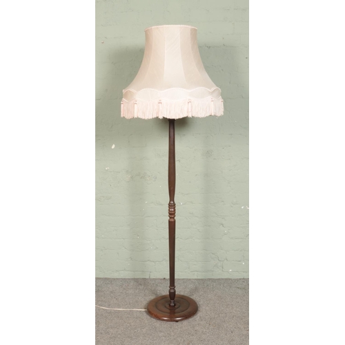 545 - A turned wooden standard lamp with fringed shade.