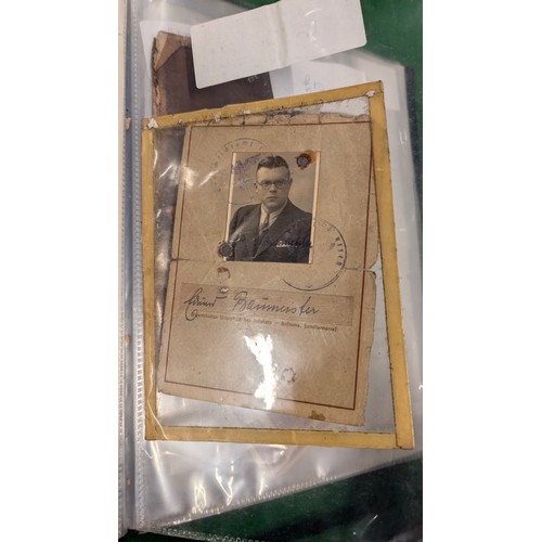 455 - A folder holding a collection of war time militaria including Hitler Youth documents, cuff titles, f... 