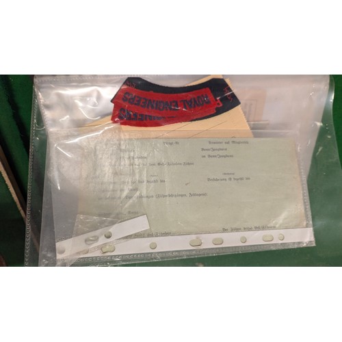 455 - A folder holding a collection of war time militaria including Hitler Youth documents, cuff titles, f... 