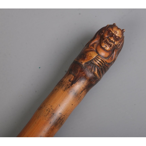 11 - A Chinese cane walking stick with carved skeletons along the body and Buddha & Devil carved on pomme... 