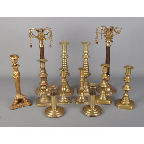 23 - A good collection of brass candlesticks to include decorative inlaid examples.