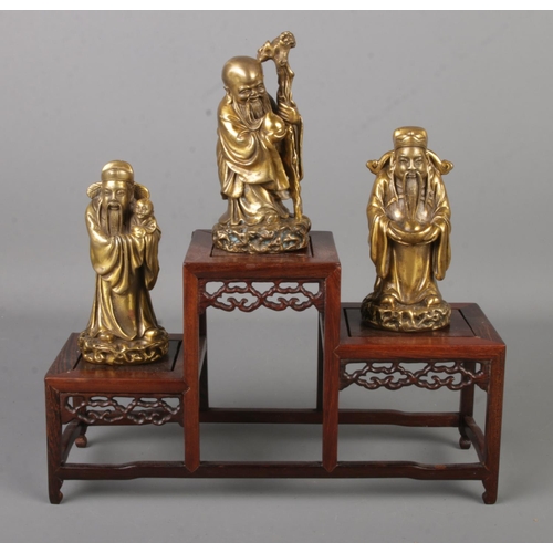 4 - Three Chinese bronze figures of sages, raised on stepped hardwood stand. Each figure bearing charact... 