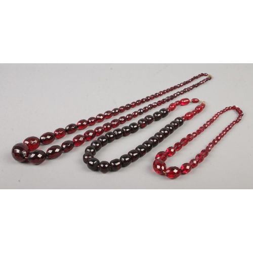 411 - Three strings of cherry coloured beads, including two faceted and graduated examples. Total weight 1... 