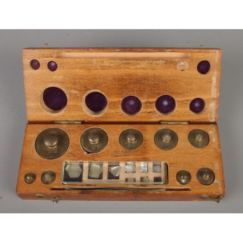 448 - A cased set of graduated jewellers weights and tweezers. Maker A. H. Baird, Edinburgh.