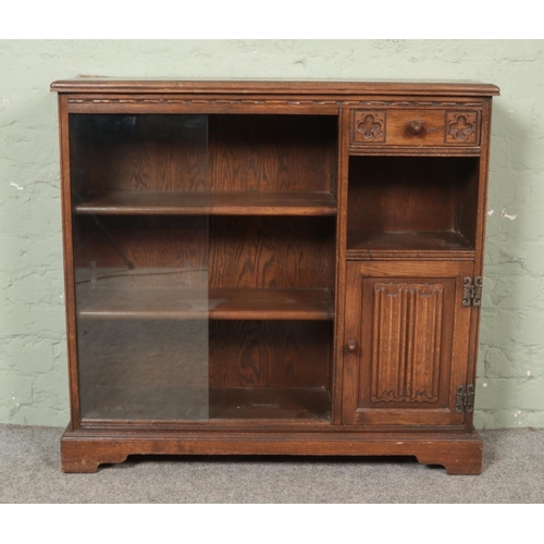 472 - An Old Charm carved oak side cabinet/book case. With glass sliding doors, single drawer and cupboard... 