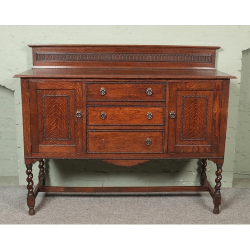 475 - A carved oak sideboard with beaded decoration and barley twist supports.