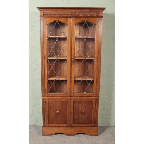 477 - A carved oak lead glazed bookcase with cupboard base.