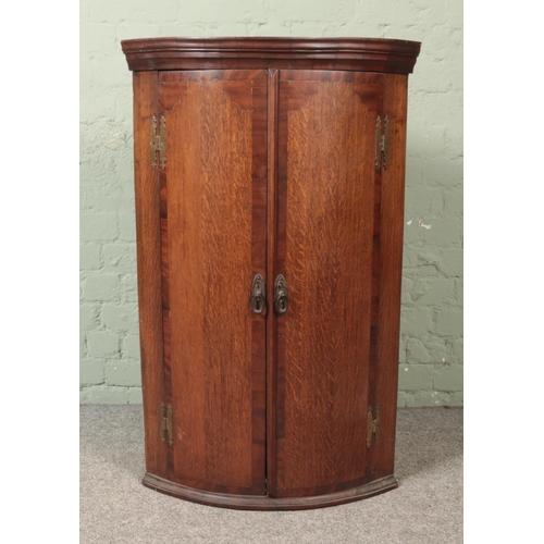 490 - A Georgian oak and mahogany bow fronted corner cupboard.