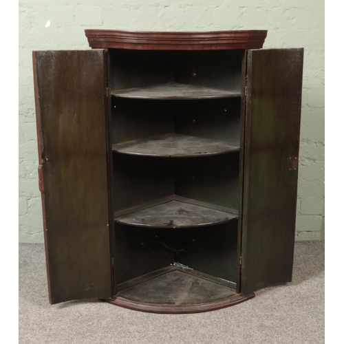 490 - A Georgian oak and mahogany bow fronted corner cupboard.