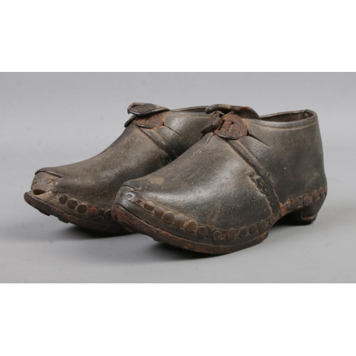 117 - An antique pair of child's shoes, with leather upper studded into horseshoe sole. 12cm long.