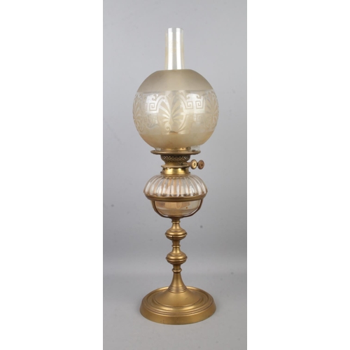 134 - A brass and glass oil lamp, produced by Hinks & Sons, with frosted shade above glass reservoir. Rais... 