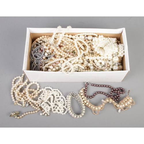 138 - A box of assorted simulated pearl necklaces and bracelets to include coloured examples.