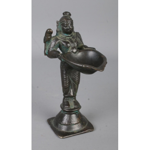 36 - A small Indian bronze figure formed as a deity holding large bowl. Approx. height 11cm.