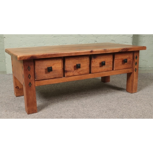 490 - A stained pine coffee table featuring double sided drawers and carved diamond details. Approx. dimen... 