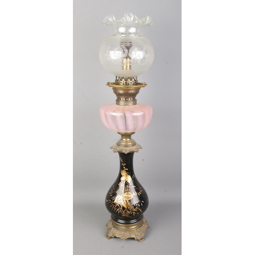 22 - A brass and glass oil lamp featuring hand painted gilt floral decoration and pink opaline reservoir.... 