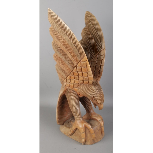 53 - A carved wooden figure of an eagle on perch with outstretched wings. Approx. height 47.5cm.