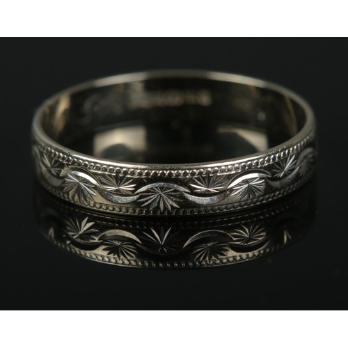 346 - An 18ct white gold ring featuring engraved decoration. Size R, 2.2g.