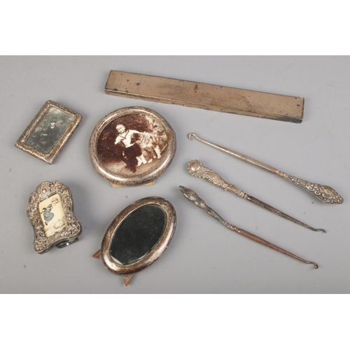 394 - A collection of small silver frames with a selection of button hooks and a piece of silver