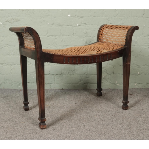 472 - A late Nineteenth/early Twentieth century mahogany window seat/stool, with bergère base. Width: 77cm... 